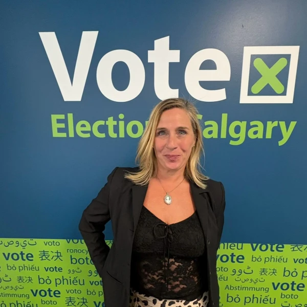 Erin Averbukh for Calgary-Acadia standing in front of an Election Calgary vote sign